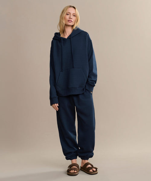 A woman in a cozy Bay Hoodie made from brushed fleece and matching sweatpants.