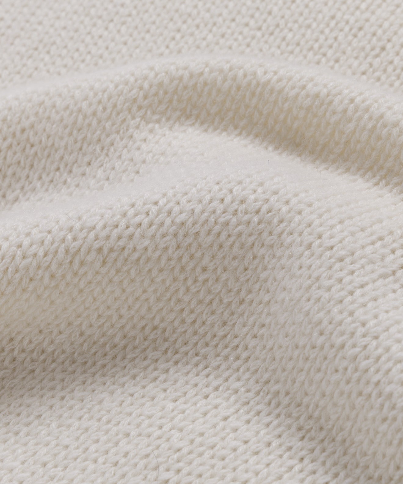 Close-up of the Cashmere Jet Turtleneck's cream-colored lightweight knit fabric, highlighting its soft texture and gentle folds—ideal for an oversized turtleneck look.